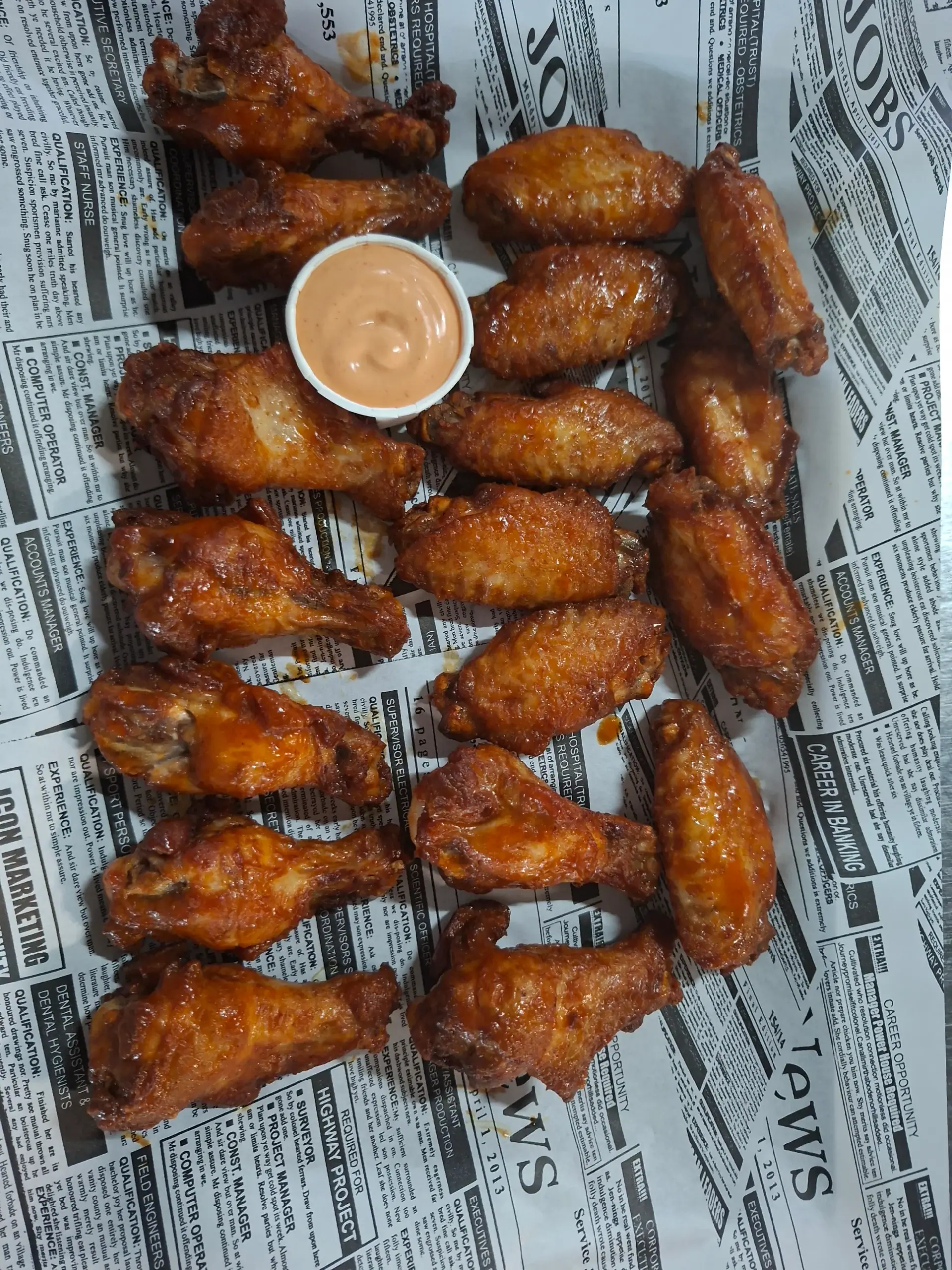 A generous spread of crispy chicken wings with a dipping sauce at Zazoo