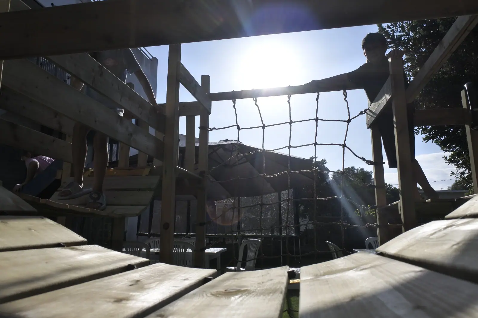A child scrambling over the outdoor climbing frame in the golden Algarve sun