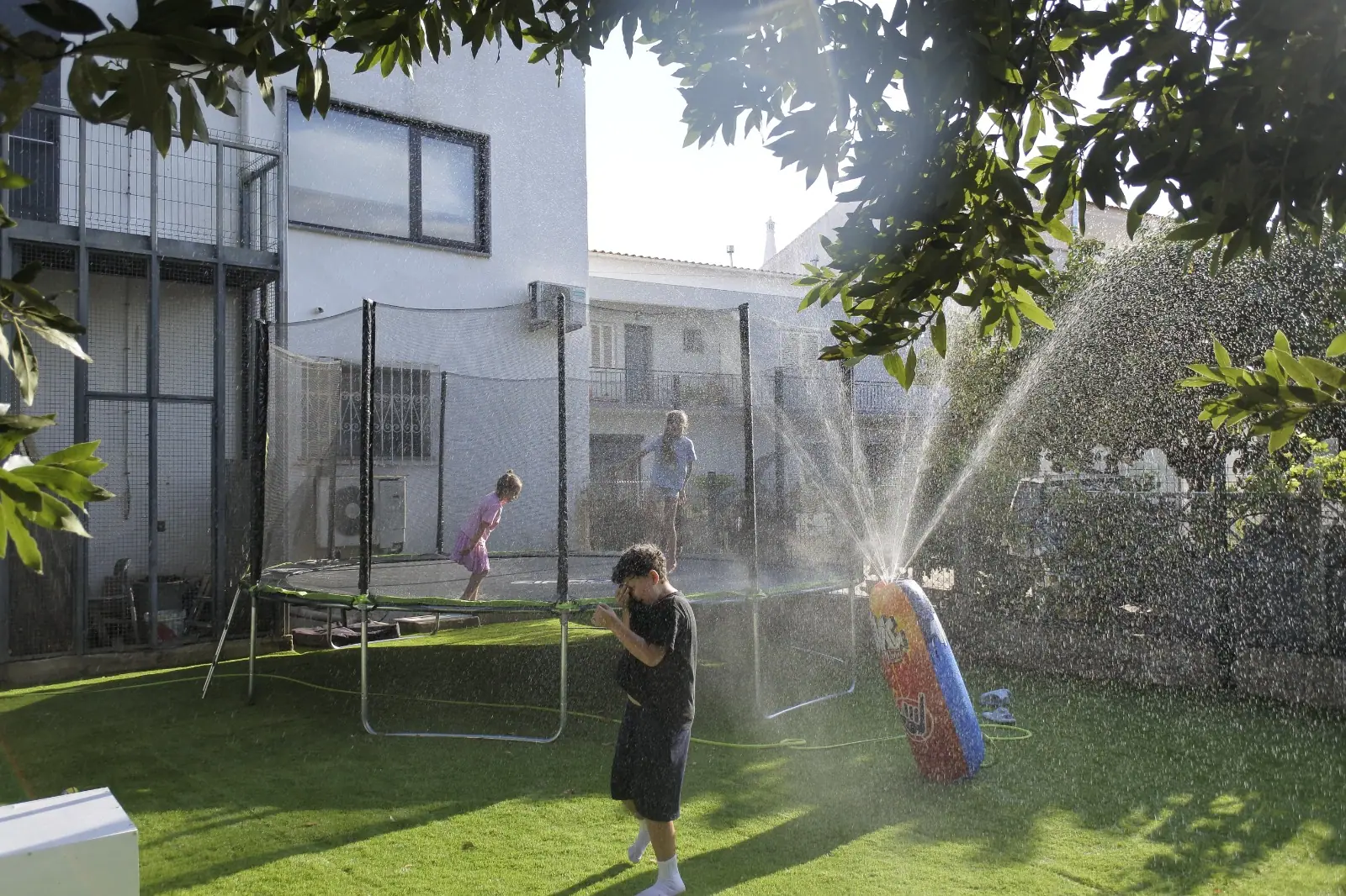 Kids cooling off in the water sprinkler on a sunny day at Zazoo